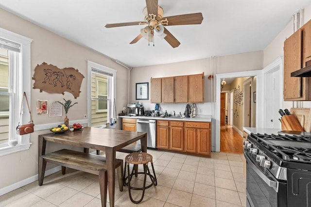 kitchen with light tile patterned floors, a ceiling fan, stainless steel appliances, and brown cabinetry