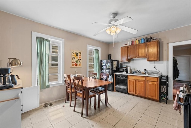 kitchen featuring ceiling fan, brown cabinets, a sink, light tile patterned floors, and black appliances