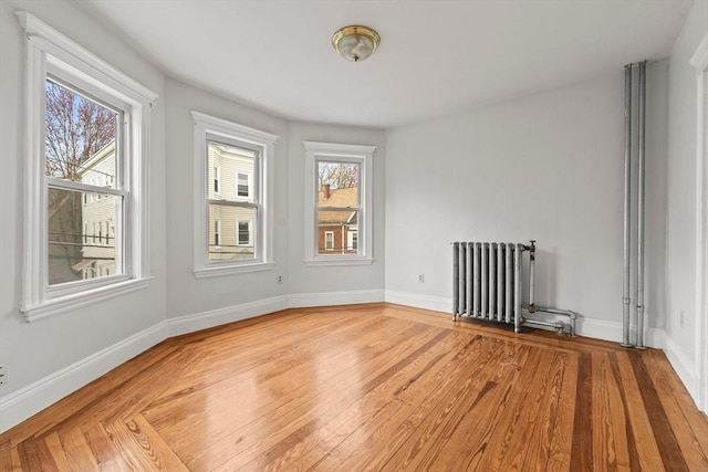 spare room featuring radiator heating unit, plenty of natural light, and light wood-type flooring