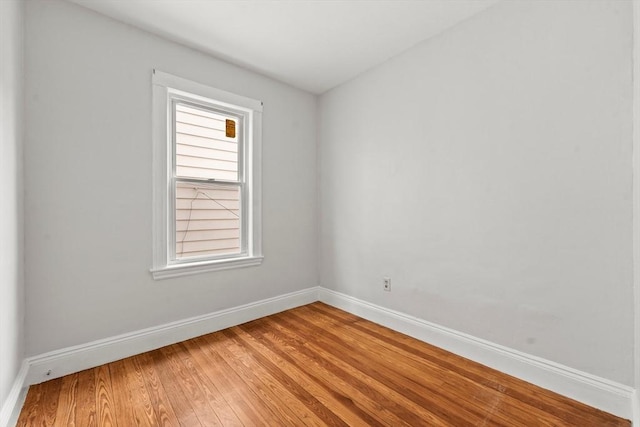 spare room featuring baseboards and light wood finished floors