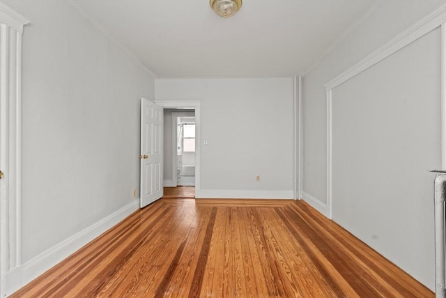 spare room with baseboards and wood finished floors