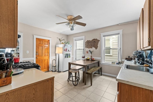 kitchen with a sink, light countertops, freestanding refrigerator, and a ceiling fan