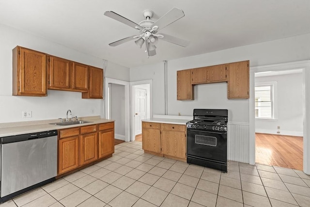kitchen featuring dishwasher, light countertops, a sink, light tile patterned floors, and black gas range oven