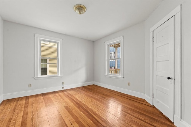 unfurnished bedroom featuring baseboards, multiple windows, and light wood finished floors