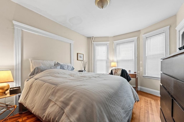 bedroom featuring baseboards, multiple windows, and hardwood / wood-style floors