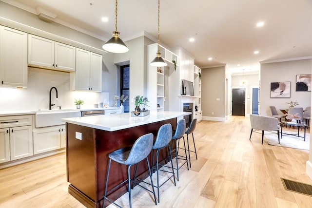 kitchen featuring crown molding, white cabinetry, sink, and pendant lighting