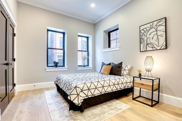 bedroom with light wood-type flooring, crown molding, and a closet