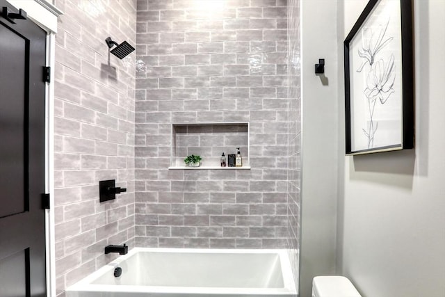 bathroom with tiled shower / bath combo and toilet