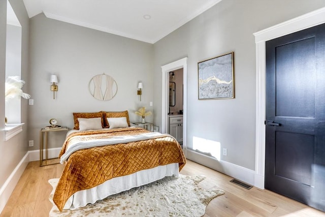 bedroom with connected bathroom, light hardwood / wood-style flooring, and crown molding