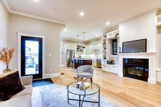 living room featuring crown molding, light hardwood / wood-style flooring, and sink