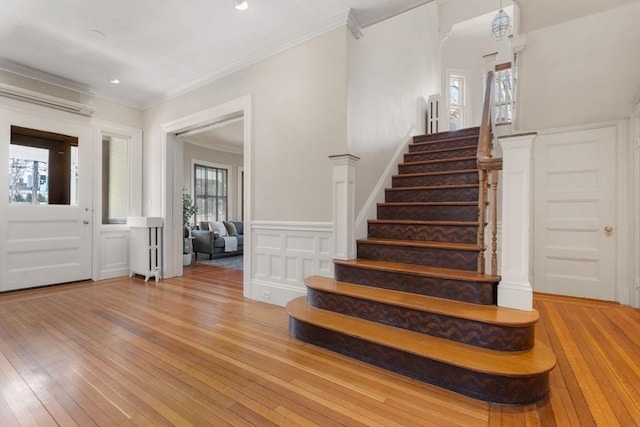 entrance foyer featuring ornamental molding, a wall mounted air conditioner, and light hardwood / wood-style flooring