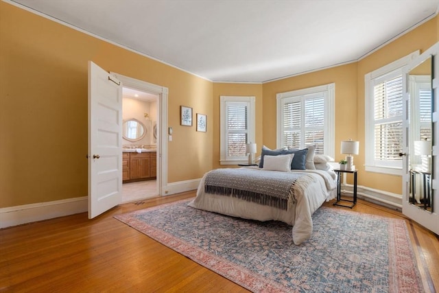 bedroom with hardwood / wood-style flooring, ornamental molding, and ensuite bathroom