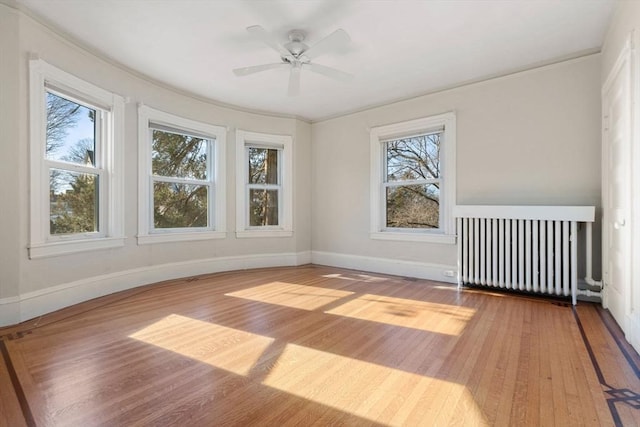 unfurnished room featuring ceiling fan, radiator, and hardwood / wood-style floors