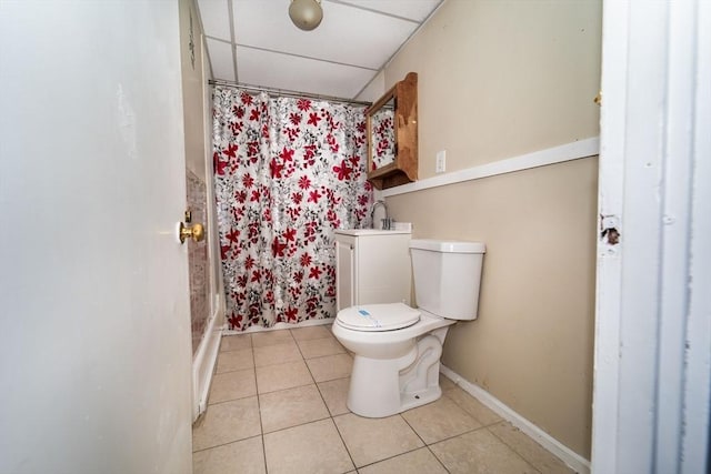 bathroom featuring toilet, a paneled ceiling, tile patterned floors, and curtained shower