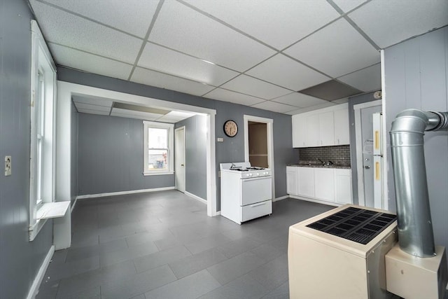 kitchen featuring white cabinetry, gas range gas stove, sink, backsplash, and a paneled ceiling