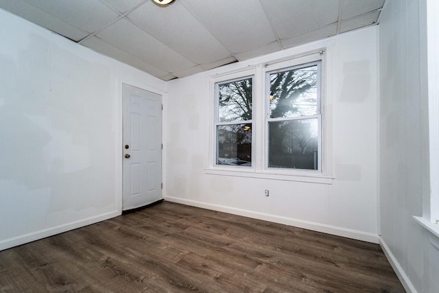 empty room with a paneled ceiling and dark hardwood / wood-style flooring