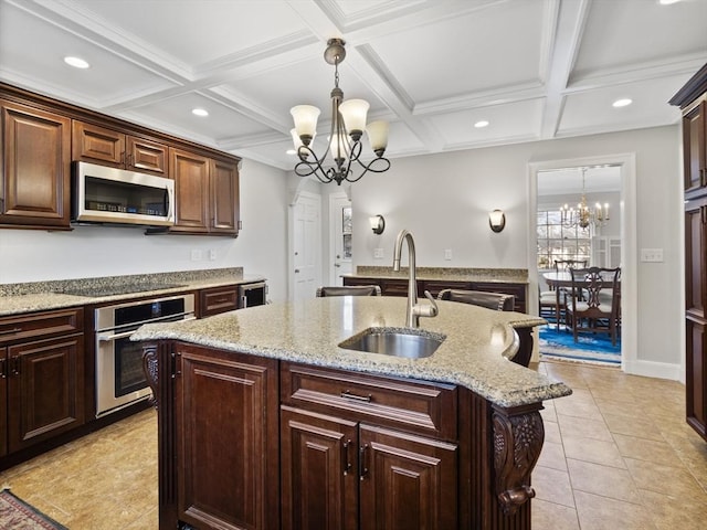 kitchen with a chandelier, decorative light fixtures, a center island with sink, appliances with stainless steel finishes, and a sink