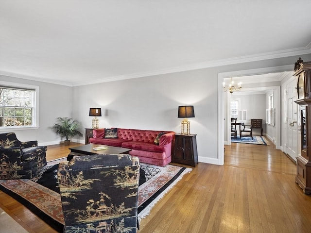 living room featuring an inviting chandelier, crown molding, baseboards, and hardwood / wood-style flooring