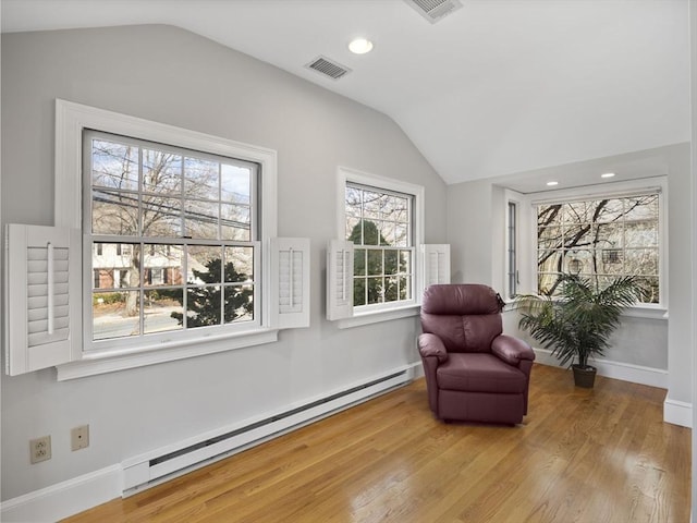 sitting room with visible vents, baseboard heating, wood finished floors, and vaulted ceiling