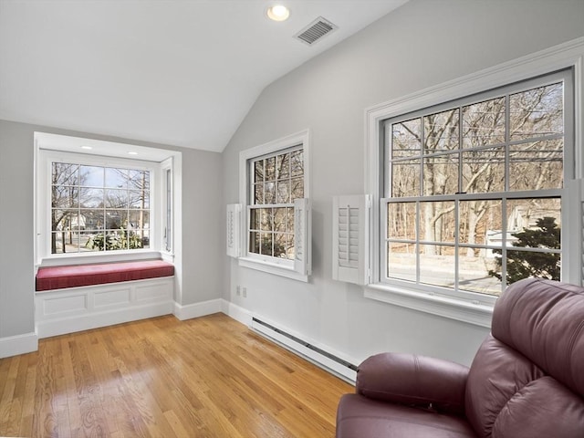 living area with visible vents, lofted ceiling, a baseboard heating unit, light wood-style floors, and baseboards