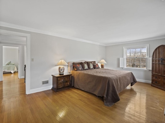 bedroom featuring visible vents, crown molding, baseboards, and hardwood / wood-style floors