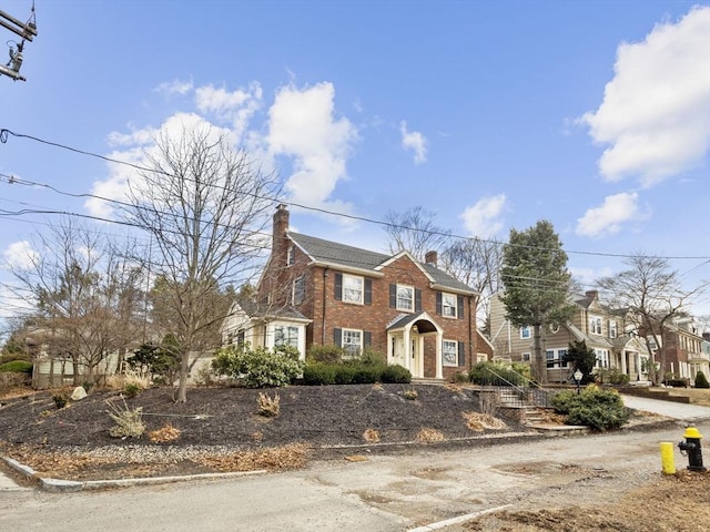 view of front of house with brick siding and a chimney