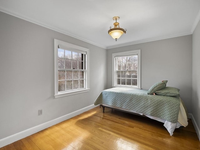 bedroom featuring ornamental molding, baseboards, and wood finished floors