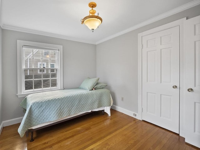 bedroom featuring crown molding, wood finished floors, and baseboards