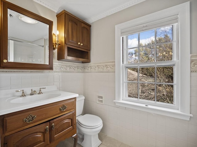 bathroom featuring a wainscoted wall, toilet, vanity, tile patterned floors, and tile walls