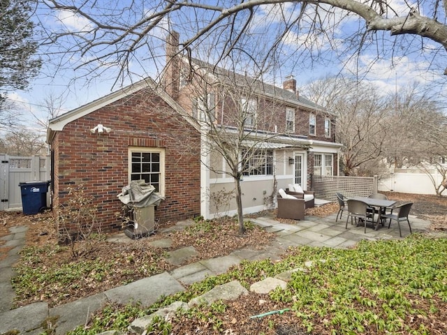 rear view of property with outdoor lounge area, brick siding, a chimney, and a patio area