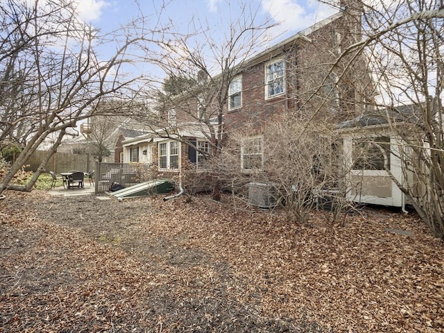 rear view of property featuring brick siding and a chimney