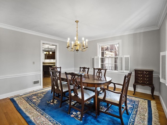 dining room featuring visible vents, baseboards, an inviting chandelier, ornamental molding, and hardwood / wood-style flooring