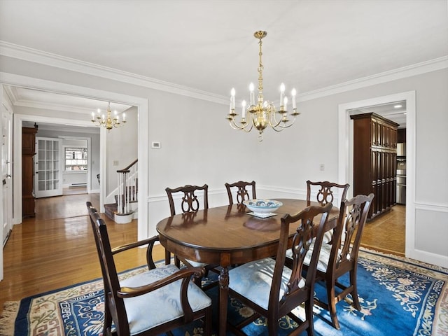 dining room with stairway, an inviting chandelier, wood finished floors, and ornamental molding