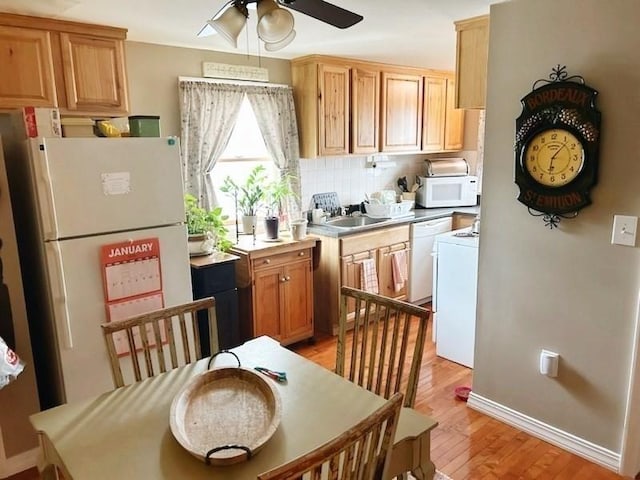 kitchen featuring white appliances, washer / dryer, decorative backsplash, sink, and light hardwood / wood-style flooring