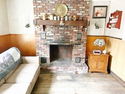 living room featuring a brick fireplace, light hardwood / wood-style floors, and wooden walls