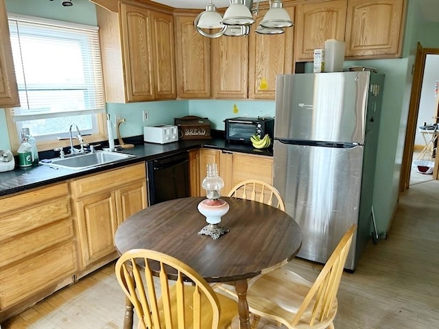 kitchen featuring black dishwasher, sink, hanging light fixtures, stainless steel refrigerator, and light hardwood / wood-style flooring