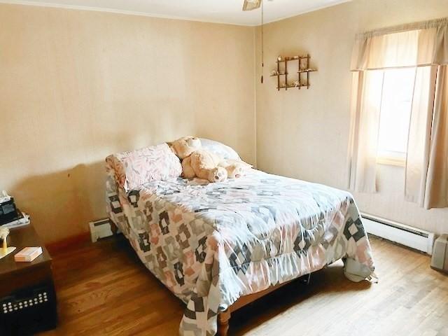 bedroom featuring ceiling fan, a baseboard radiator, and hardwood / wood-style floors