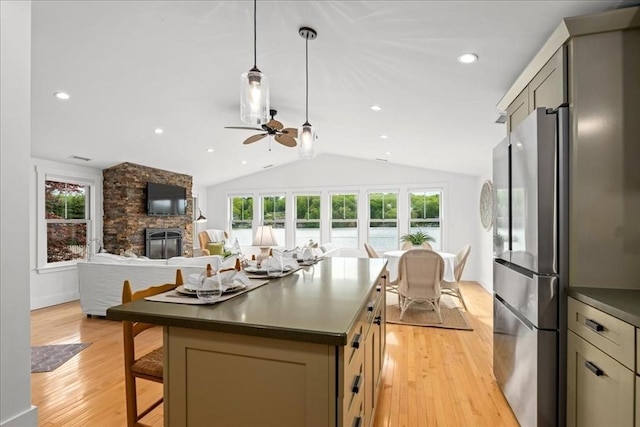 166 Klondike Rd, Dudley, MA 01571 - kitchen with freestanding refrigerator, dark countertops, a stone fireplace, a ceiling fan, and lofted ceiling