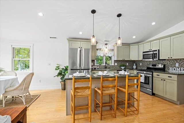 166 Klondike Rd, Dudley, MA 01571 - kitchen with stainless steel appliances, decorative backsplash, dark countertops, a kitchen bar, and light wood-style flooring