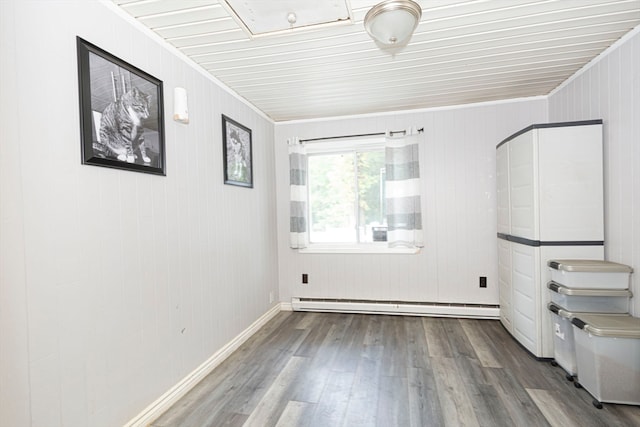 interior space with a baseboard radiator, wooden walls, hardwood / wood-style floors, and crown molding