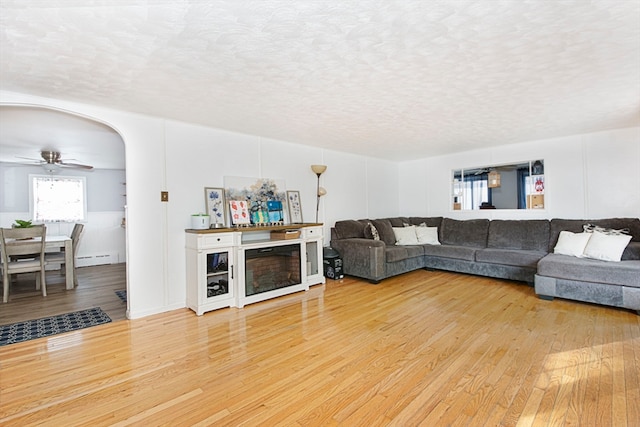 living room with a textured ceiling, a baseboard heating unit, ceiling fan, and hardwood / wood-style flooring