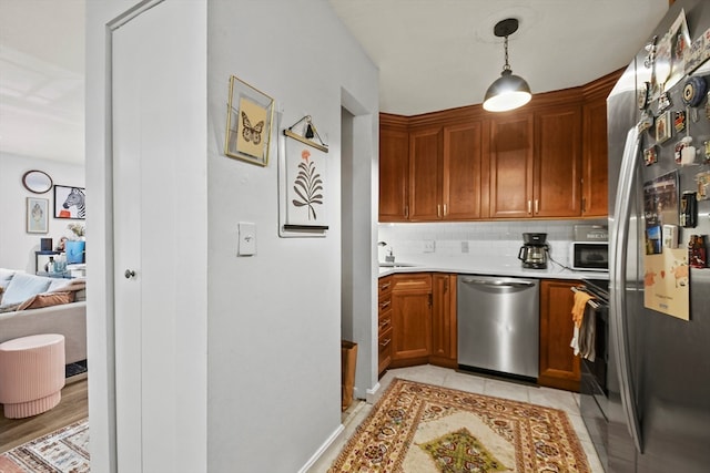 kitchen featuring light hardwood / wood-style floors, tasteful backsplash, decorative light fixtures, sink, and appliances with stainless steel finishes