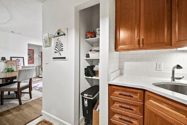 kitchen with decorative backsplash, light stone countertops, hardwood / wood-style floors, and sink