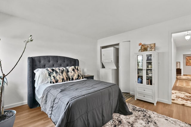 bedroom with stacked washer / dryer and light hardwood / wood-style flooring