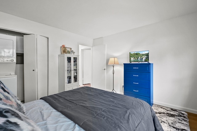 bedroom featuring stacked washing maching and dryer and hardwood / wood-style flooring