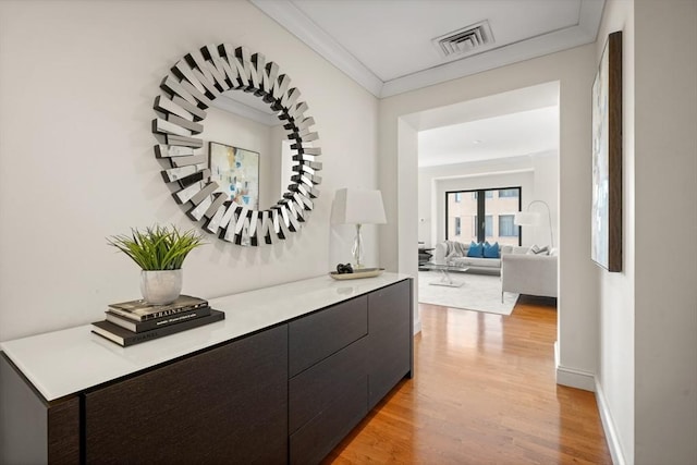 hallway with light wood finished floors, crown molding, and baseboards