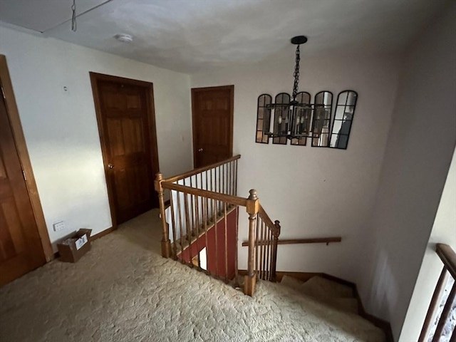 stairway with a notable chandelier and carpet