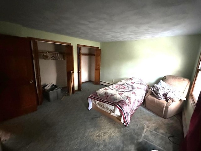 carpeted bedroom featuring a baseboard heating unit and two closets