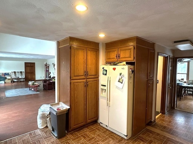 kitchen featuring white refrigerator with ice dispenser and a textured ceiling