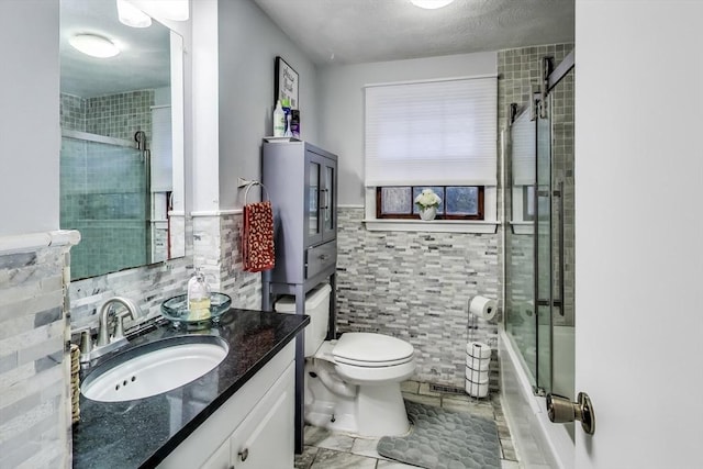 full bathroom featuring tile walls, vanity, enclosed tub / shower combo, and toilet